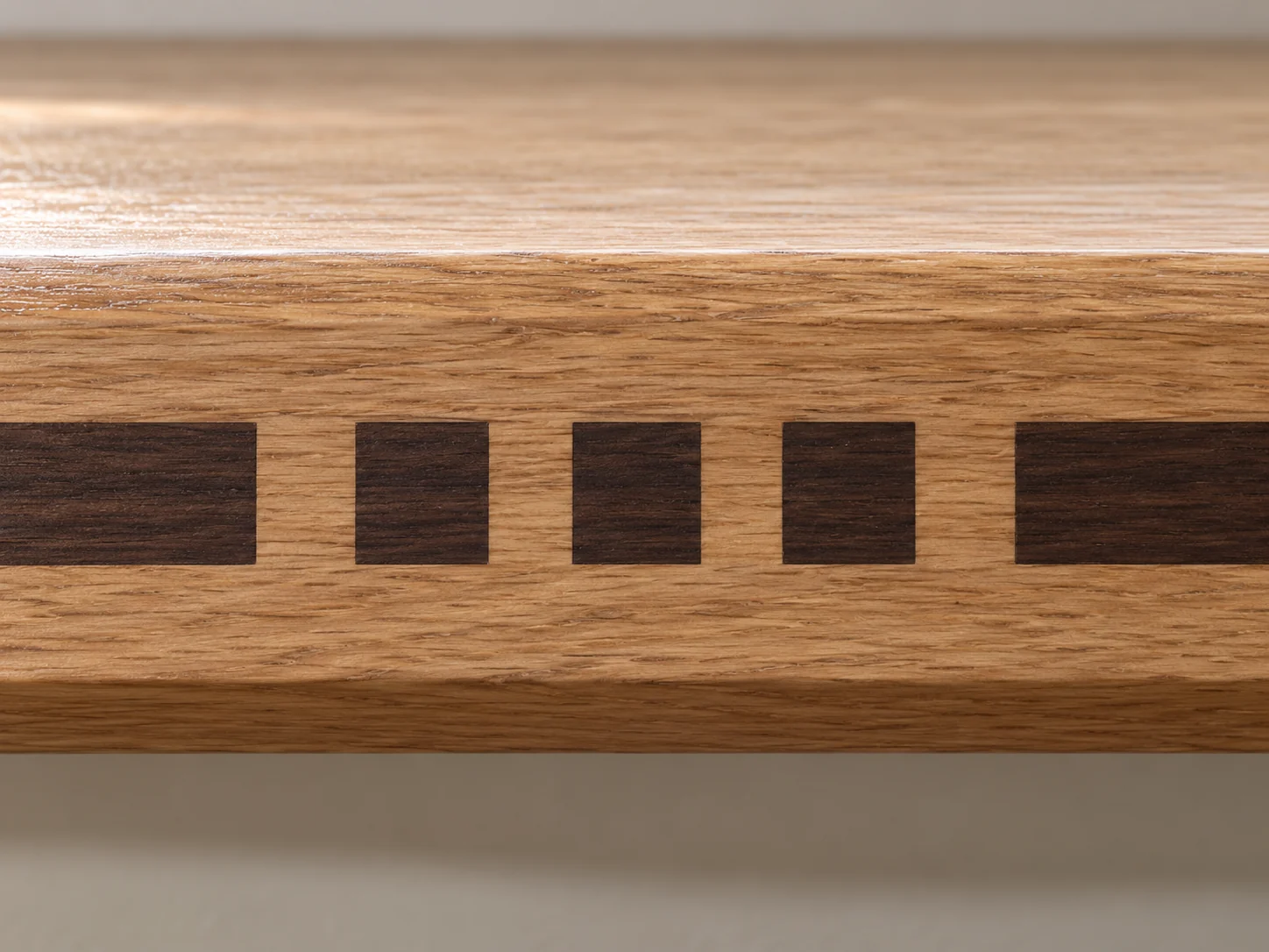 Close view of the three square inlays let flush into the front edge of a white oak window sill